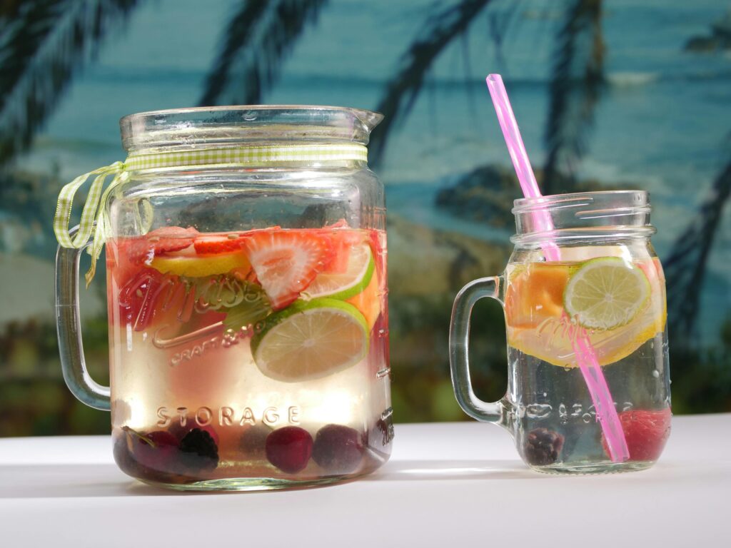 Cool off with fruit-infused water in mason jars, perfect for a sunny beach day.